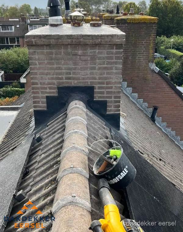 Schoorsteen met loodaansluiting en nokvorst op pannendak in Eersel