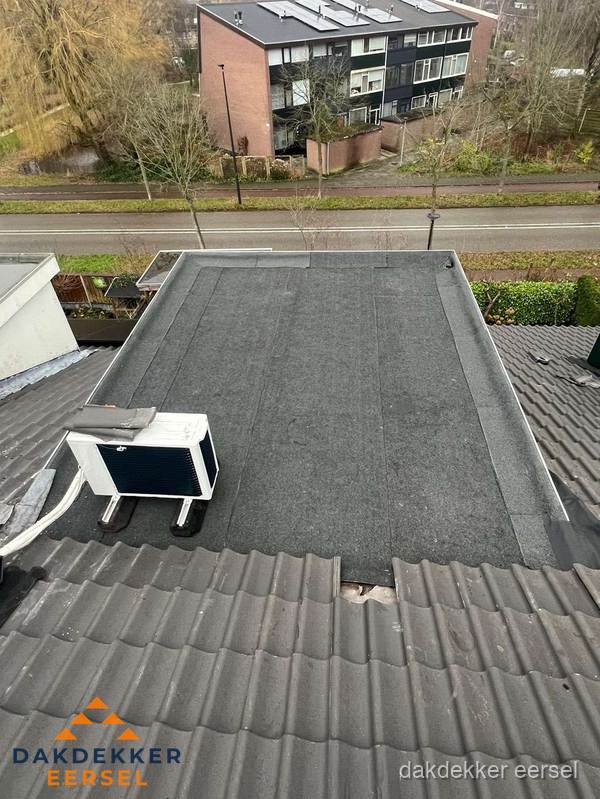 Plat dak inspectie met bitumen bedekking naast schuin pannendak in Eersel