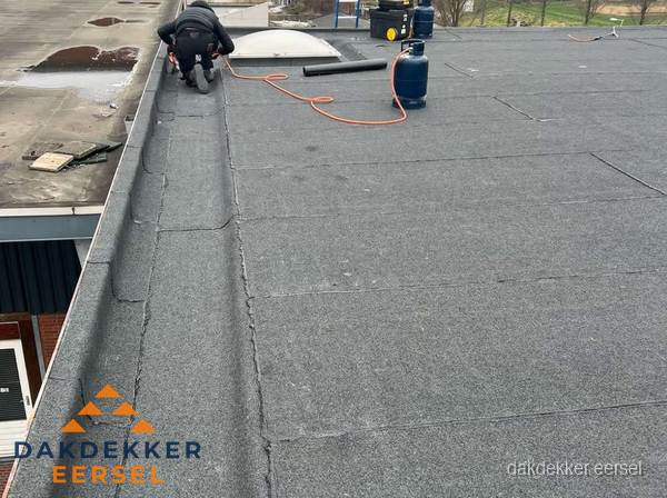 Dakdekker repareert bitumen dakbedekking op groot plat dak in Eersel