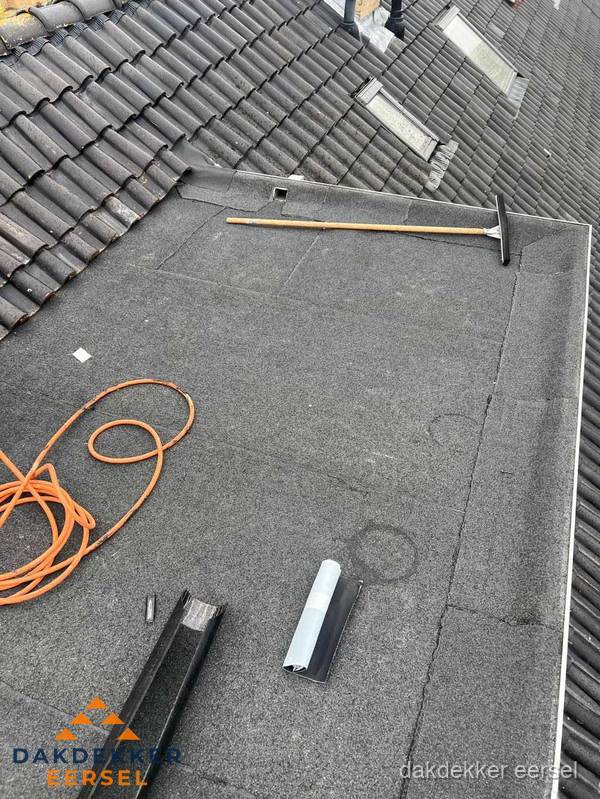 Plat dak reparatie met gereedschap en loodstroken in Eersel