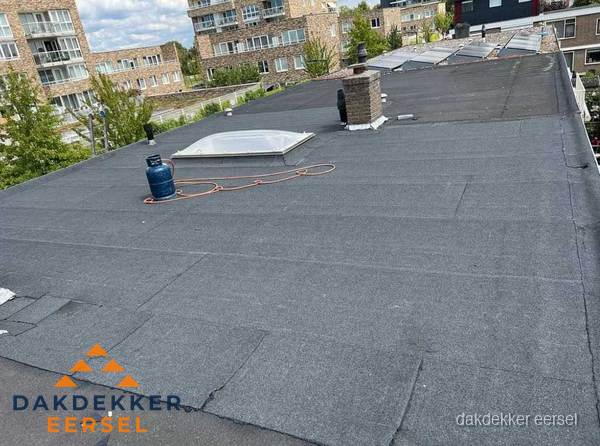 Bitumen dakbedekking op plat dak met lichtkoepel en schoorsteen in Eersel