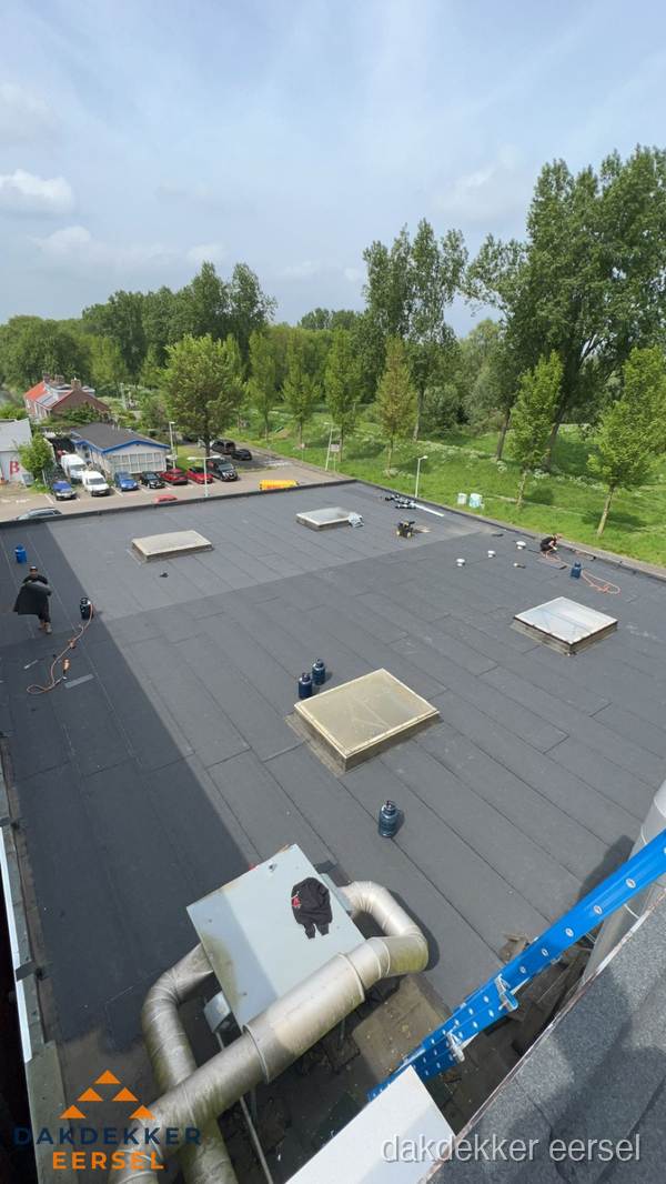 Dakdekker aan het werk op groot plat dak met bitumen in Eersel